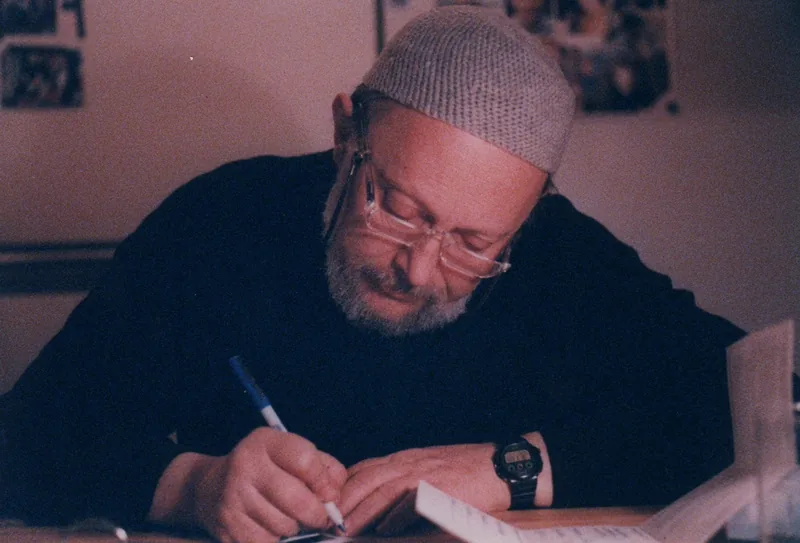 Arnold Schwarzbart at his drawing table, drawing with a pen